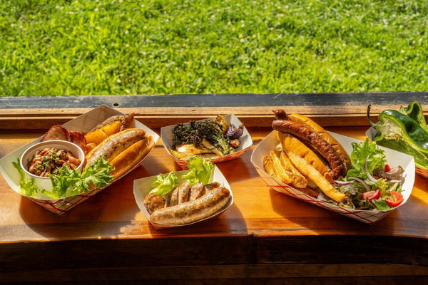 Assorted Dufour Gourmet grilled sausages served with buns, beans, fries, and vegetables