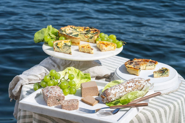 Elegant lakeside food presentation with pâté, quiches, grapes and white serving plates