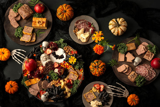 Halloween charcuterie board with French pâtés, cured meats, cheeses, pumpkins and spooky decorations
